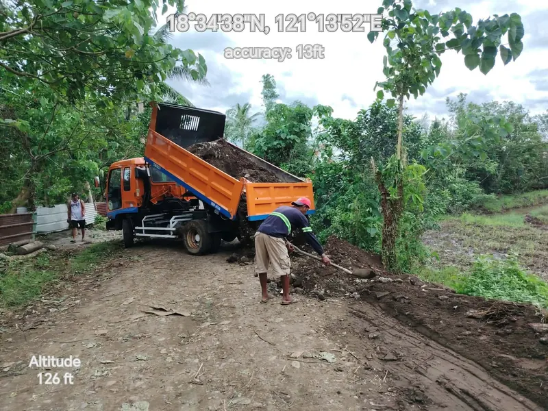 Dump truck delivering fill material to a road bed, geotagged field photo