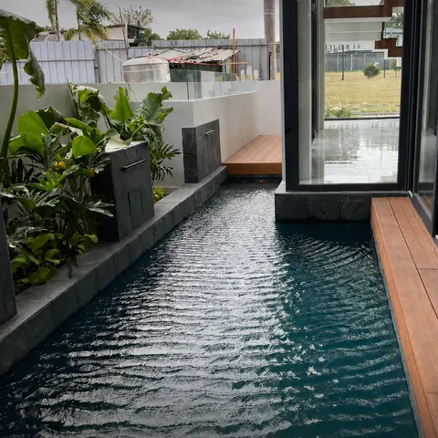 Courtyard pool lined with timber decking and garden planting