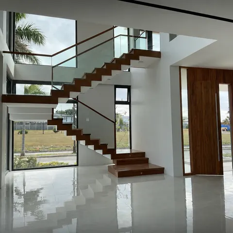 Double-height stair hall with floating timber steps and a glass balustrade