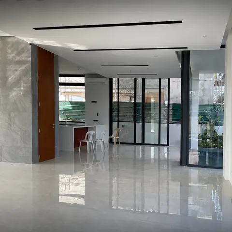 Bright open-plan living area with polished stone floors and full-height glass