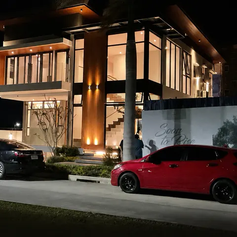 The home at night seen from the street, with cars in the driveway